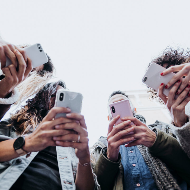 Group of young people looking at their smartphones in the street